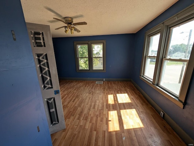 empty room with ceiling fan, hardwood / wood-style flooring, and a textured ceiling