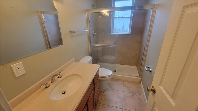 bathroom featuring tile patterned flooring, vanity, toilet, and a shower with shower door