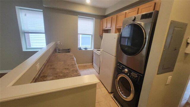 laundry room featuring sink, light tile patterned floors, and stacked washer and clothes dryer