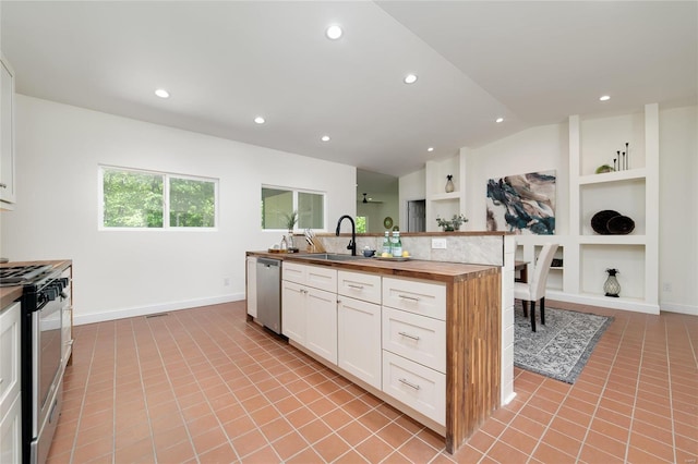 kitchen featuring light tile patterned flooring, an island with sink, white cabinetry, stainless steel appliances, and built in features