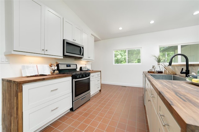 kitchen with appliances with stainless steel finishes, white cabinets, wood counters, sink, and plenty of natural light