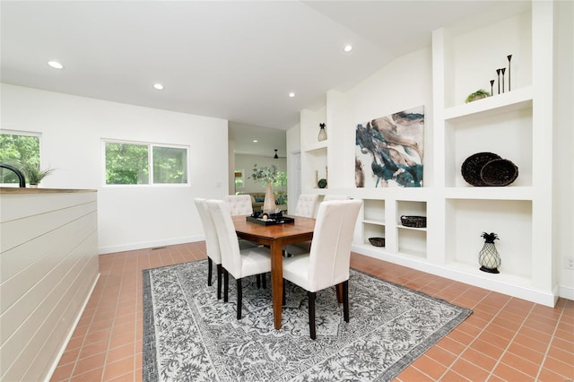 tiled dining room featuring built in shelves and lofted ceiling