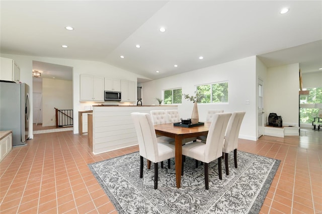 dining area with light tile patterned flooring and vaulted ceiling