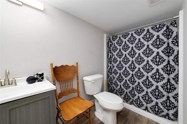 bathroom with wood-type flooring, vanity, walk in shower, and toilet