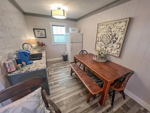 dining room with hardwood / wood-style floors, sink, and ornamental molding