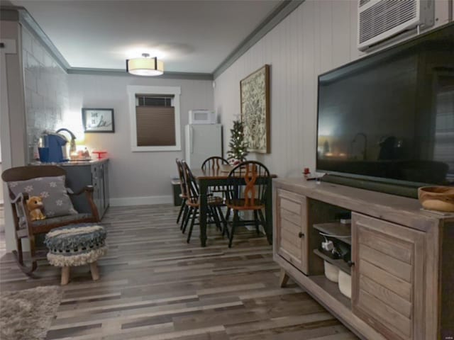 interior space with ornamental molding, a wall mounted air conditioner, and hardwood / wood-style flooring