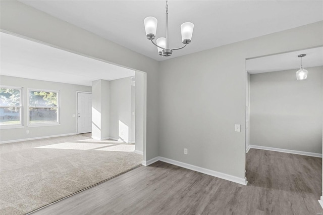 empty room featuring a notable chandelier and hardwood / wood-style flooring