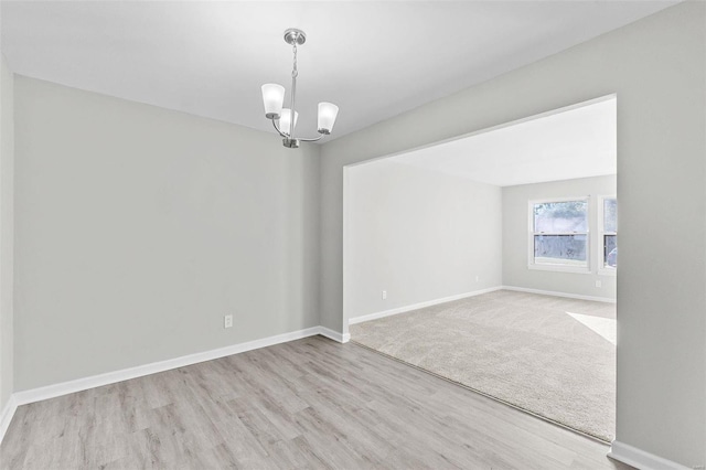 spare room featuring light hardwood / wood-style flooring and a chandelier