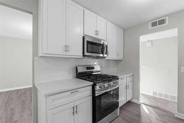 kitchen with light hardwood / wood-style flooring, stainless steel appliances, and white cabinetry