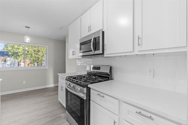 kitchen with pendant lighting, light hardwood / wood-style floors, white cabinetry, backsplash, and appliances with stainless steel finishes