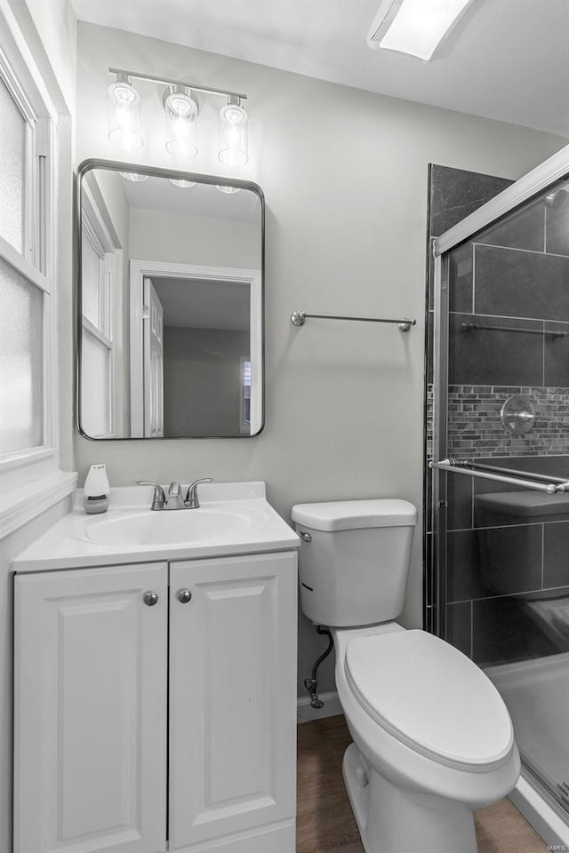 bathroom featuring hardwood / wood-style floors, walk in shower, vanity, and toilet