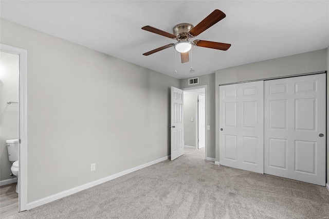 unfurnished bedroom with light carpet, ceiling fan, ensuite bathroom, and a closet