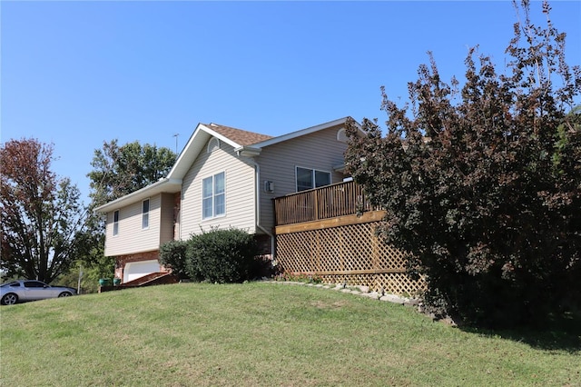 view of side of home with a deck, a yard, and a garage