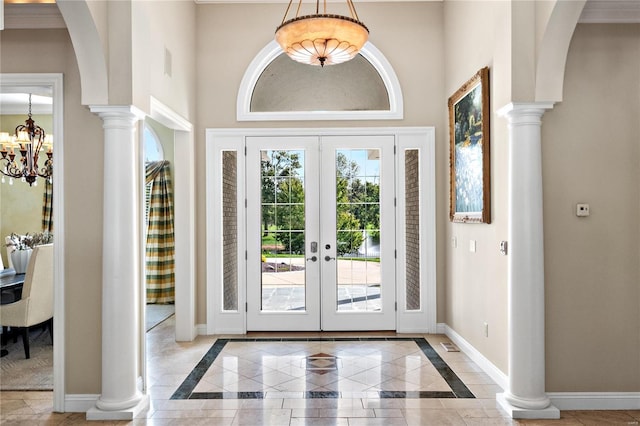 entryway with ornamental molding, a high ceiling, french doors, and an inviting chandelier