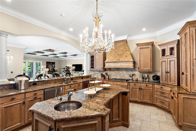 kitchen featuring custom exhaust hood, hanging light fixtures, sink, kitchen peninsula, and a kitchen island with sink