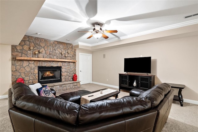 living room with ornamental molding, ceiling fan, a stone fireplace, and light colored carpet