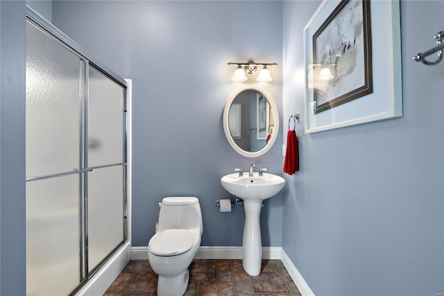 bathroom with a shower with shower door and toilet