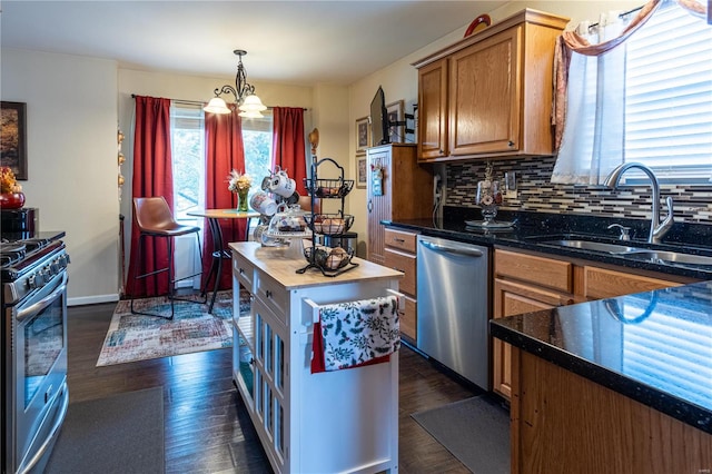 kitchen with tasteful backsplash, pendant lighting, stainless steel appliances, dark hardwood / wood-style floors, and sink