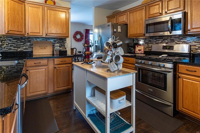 kitchen featuring stainless steel appliances, backsplash, dark stone countertops, and dark hardwood / wood-style floors