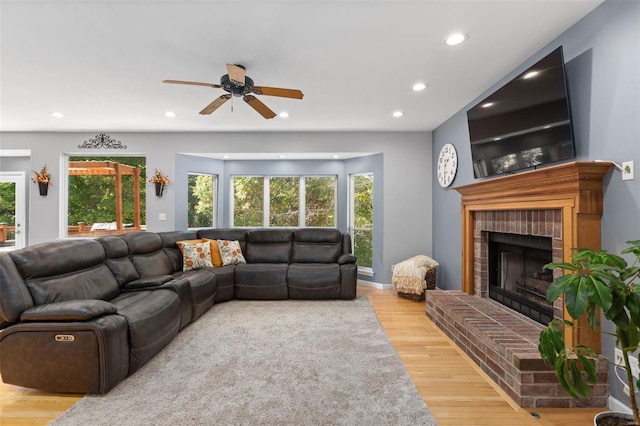 living room featuring a brick fireplace, light hardwood / wood-style floors, and ceiling fan