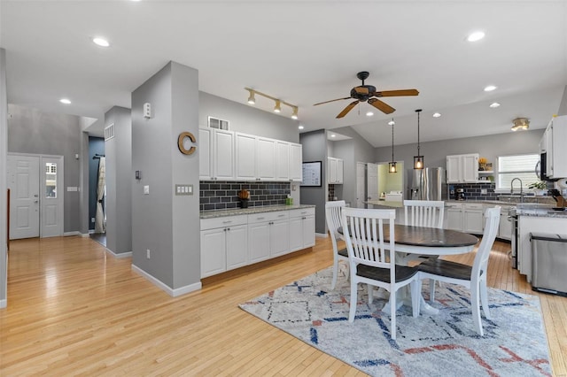 dining area with sink, ceiling fan, vaulted ceiling, and light hardwood / wood-style flooring