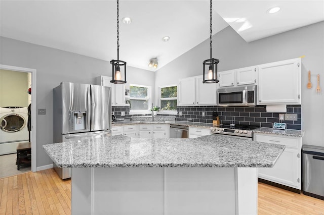 kitchen featuring hanging light fixtures, white cabinets, appliances with stainless steel finishes, and washer / dryer