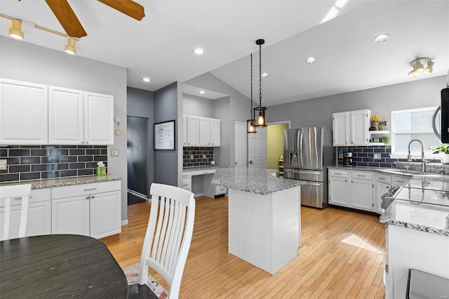 kitchen with a center island, white cabinetry, hanging light fixtures, appliances with stainless steel finishes, and backsplash