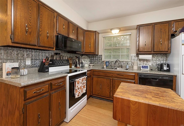 kitchen with sink, wooden counters, tasteful backsplash, light hardwood / wood-style flooring, and black appliances