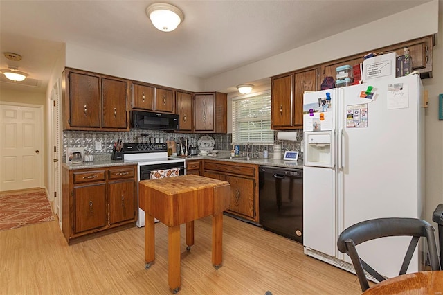 kitchen featuring decorative backsplash, light wood-type flooring, black appliances, and sink