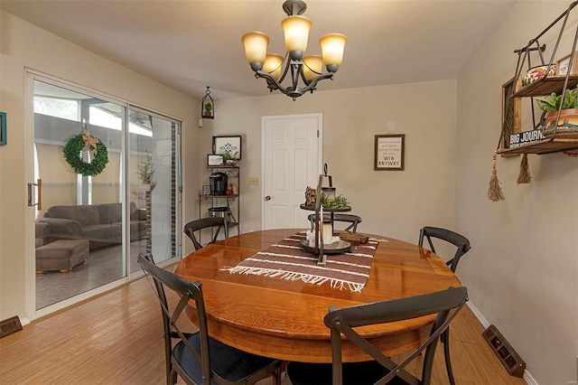 dining area with wood-type flooring and an inviting chandelier