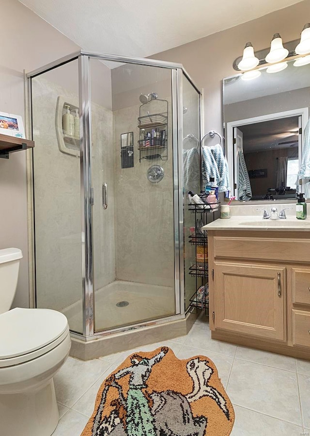 bathroom with vanity, toilet, tile patterned floors, and a shower with door