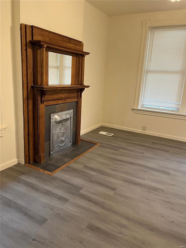 unfurnished living room featuring dark hardwood / wood-style flooring and a tiled fireplace