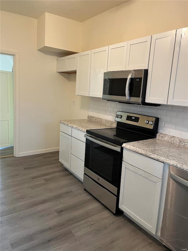 kitchen with light stone counters, stainless steel appliances, backsplash, dark hardwood / wood-style floors, and white cabinets