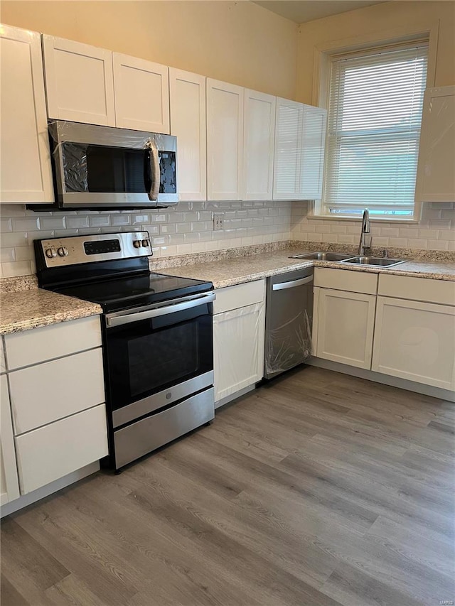 kitchen with light hardwood / wood-style flooring, appliances with stainless steel finishes, sink, and white cabinets