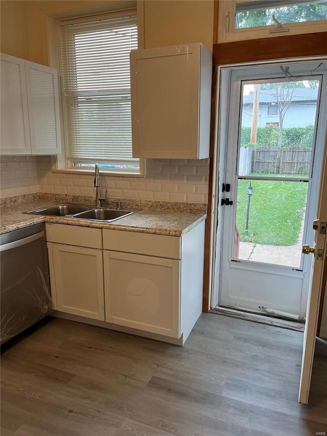 kitchen with stainless steel dishwasher, white cabinetry, sink, and light hardwood / wood-style flooring