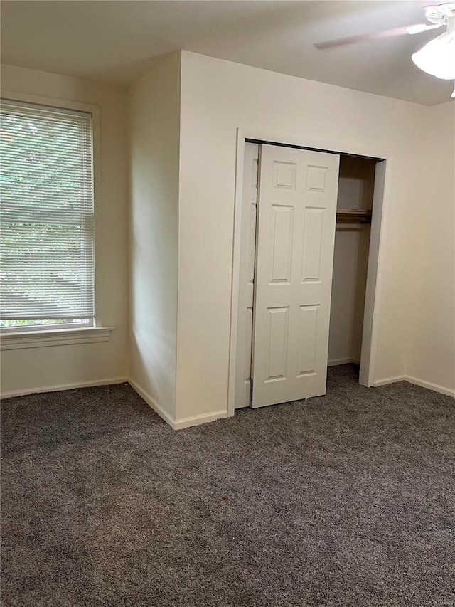 unfurnished bedroom featuring a closet, dark carpet, and ceiling fan