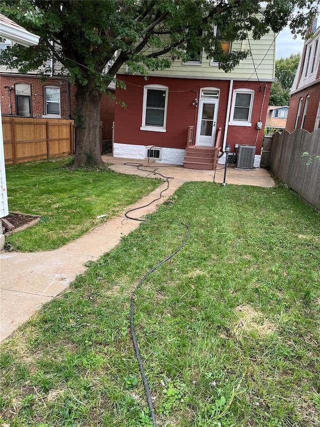 back of property with central AC unit and a lawn