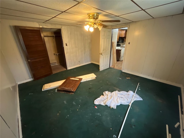 unfurnished bedroom with a drop ceiling, ceiling fan, and a closet