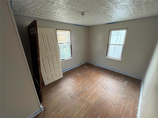 spare room featuring a textured ceiling and dark wood-type flooring