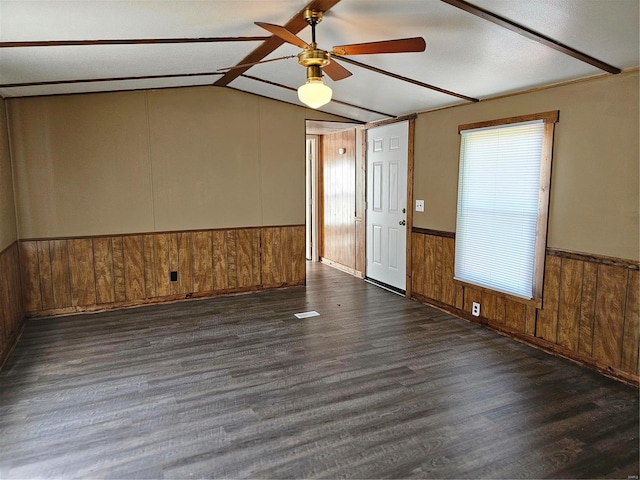 spare room featuring lofted ceiling, wood walls, dark hardwood / wood-style flooring, and ceiling fan