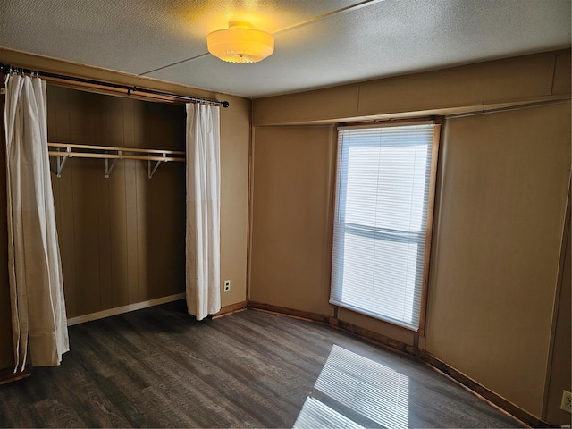 unfurnished bedroom with a textured ceiling, a closet, and dark hardwood / wood-style flooring