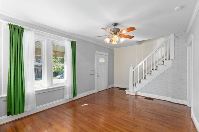 entryway featuring ornamental molding, ceiling fan, brick wall, and dark hardwood / wood-style flooring