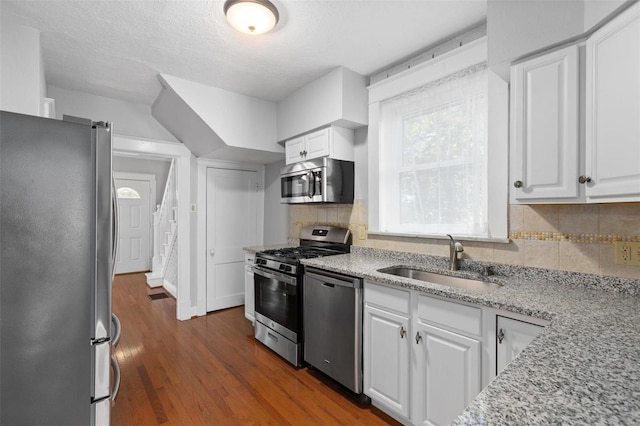 kitchen with tasteful backsplash, white cabinets, sink, dark hardwood / wood-style flooring, and appliances with stainless steel finishes