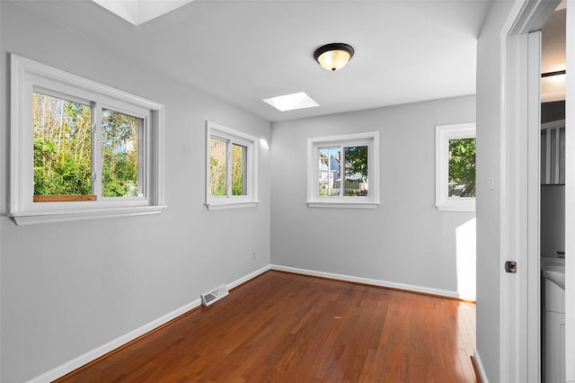 empty room featuring a skylight and dark hardwood / wood-style floors