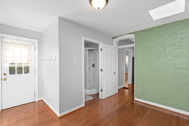 interior space with a skylight, hardwood / wood-style flooring, and ensuite bath