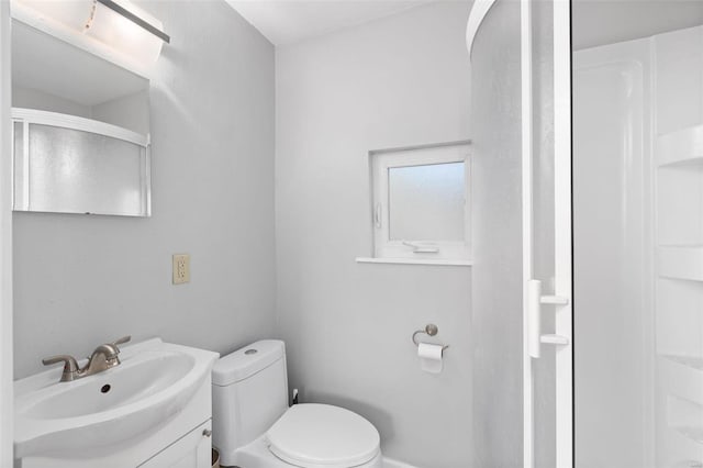 bathroom featuring an enclosed shower, toilet, and vanity