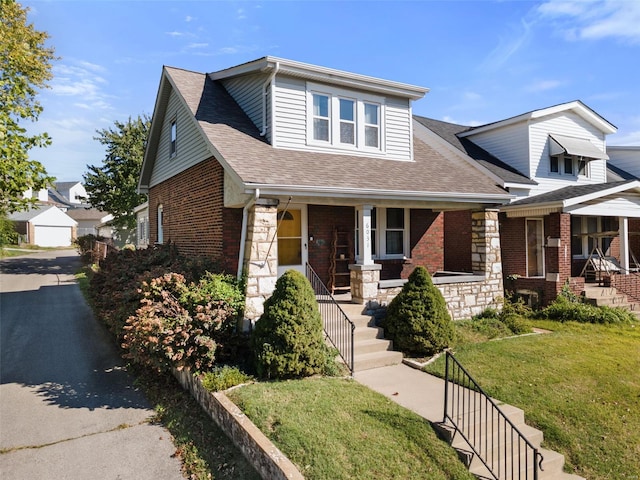 view of front of home featuring a front yard, a garage, a porch, and an outbuilding