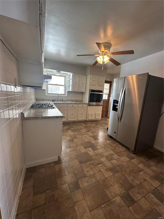 kitchen featuring sink, ceiling fan, stainless steel appliances, decorative backsplash, and white cabinets