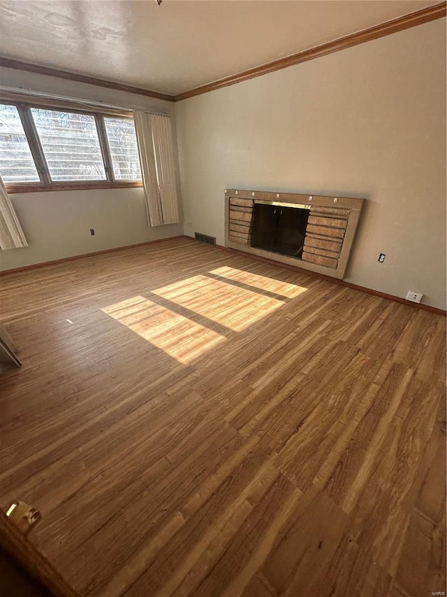 unfurnished living room with wood-type flooring and ornamental molding