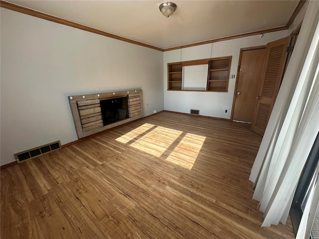 unfurnished living room featuring hardwood / wood-style flooring, ornamental molding, and a fireplace